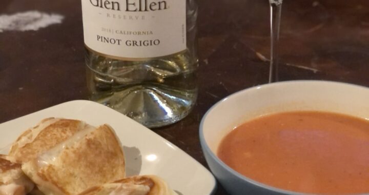 Crispy grilled cheese on toasted sourdough bread with gooey melted cheese, served alongside classic tomato soup.