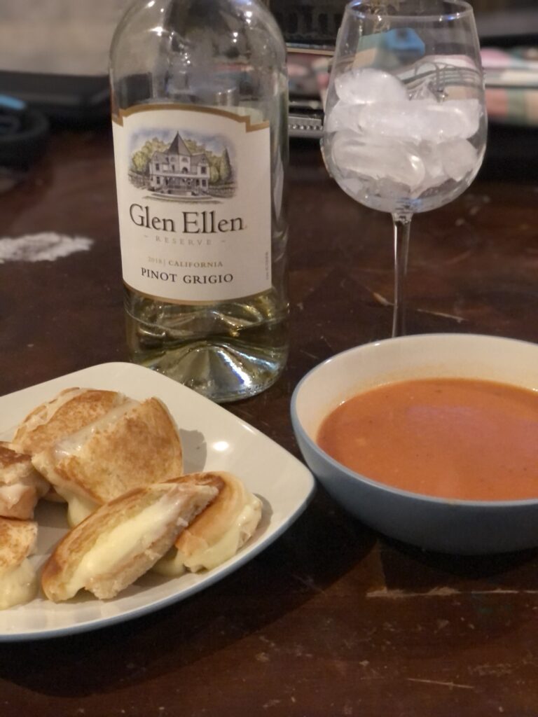 Crispy grilled cheese on toasted sourdough bread with gooey melted cheese, served alongside classic tomato soup.