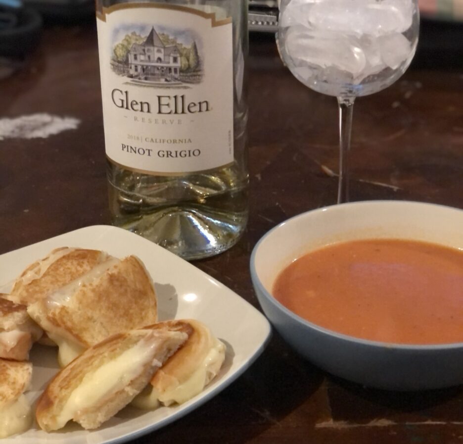 Crispy grilled cheese on toasted sourdough bread with gooey melted cheese, served alongside classic tomato soup.